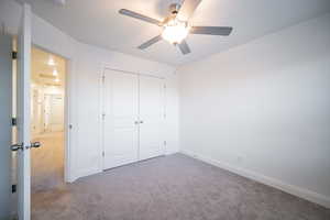 Unfurnished bedroom featuring a ceiling fan, baseboards, carpet, and a closet