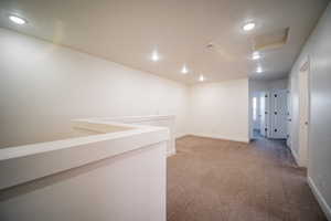Carpeted spare room featuring attic access, baseboards, and recessed lighting