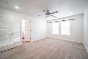 Empty room with visible vents, light carpet, baseboards, and ceiling fan