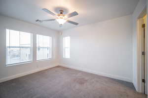 Carpeted spare room featuring ceiling fan, baseboards, and visible vents