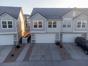 View of front of home featuring concrete driveway, stone siding, cooling unit, and a garage