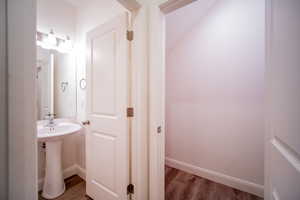 Bathroom featuring baseboards, wood finished floors, and a sink