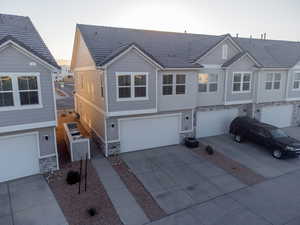 View of front of property featuring stone siding, driveway, central AC, and a garage