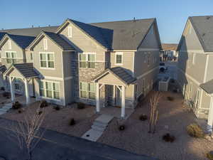View of front facade with a patio area, central AC, and stone siding