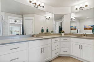 Full bath featuring tile patterned floors, double sinks, a textured ceiling