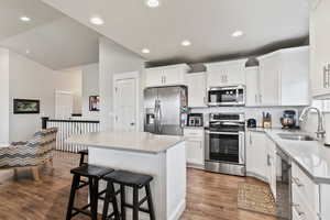 Kitchen with a kitchen bar, LVP flooring, a sink, backsplash, and appliances with stainless steel finishes