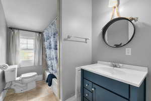 Full bathroom featuring tile patterned flooring, toilet, vanity, baseboards, and a textured ceiling