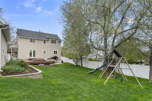 View of yard featuring a fenced backyard, a deck, a playground, and french doors