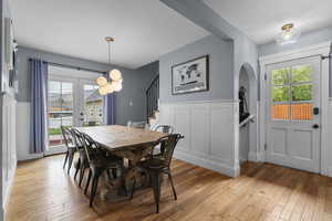 Dining space featuring arched walkways, wainscoting, stairs, and french doors