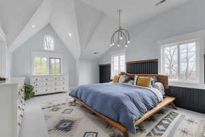 Bedroom with vaulted ceiling, multiple windows, and visible vents