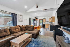 Living area with light wood finished floors, attic access, vaulted ceiling, and plenty of natural light
