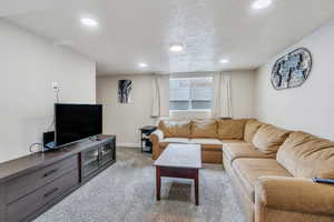 Carpeted living area with recessed lighting, a textured ceiling, and baseboards