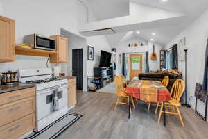 Dining space with vaulted ceiling, light wood-style floors, and recessed lighting