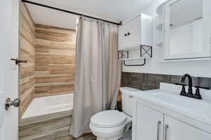 Bathroom featuring shower / tub combo with curtain, vanity, and toilet
