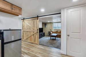 Kitchen featuring a barn door, light wood-style floors, freestanding refrigerator, baseboards, and recessed lighting