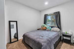 Carpeted bedroom with recessed lighting, electric panel, and baseboards