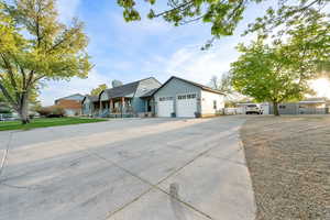 Single story home with a chimney, an attached garage, driveway, and covered porch
