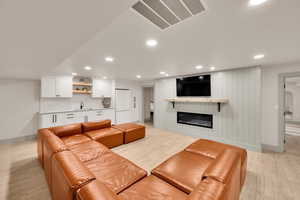 Living room with recessed lighting, light wood-type flooring, visible vents, and indoor wet bar