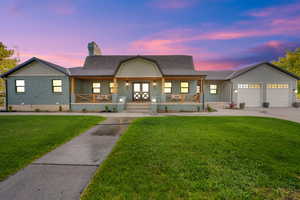View of front facade featuring a chimney, concrete driveway, a porch, a yard, and a garage
