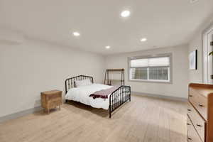 Bedroom with light wood finished floors, baseboards, and recessed lighting