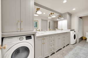 Washroom with washer / dryer, a sink, laundry area, and recessed lighting