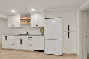 Kitchen featuring open shelves, a sink, freestanding refrigerator, white cabinetry, and recessed lighting