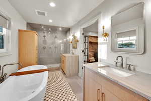 Full bathroom with two vanities, visible vents, a wealth of natural light, and a sink