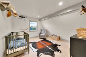 Bedroom with a wall mounted air conditioner, wood finished floors, and recessed lighting