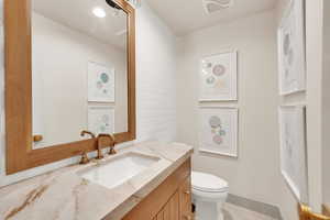 Half bath with visible vents, vanity, and toilet