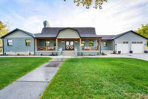 View of front of house featuring a chimney, a garage, a front yard, and covered porch