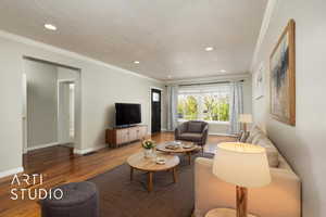 Living room with ornamental molding, wood finished floors, and recessed lighting