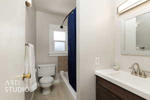 Bathroom with tile patterned flooring, toilet, vanity, baseboards, and shower / tub combo