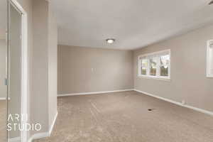 Carpeted empty room featuring baseboards and visible vents