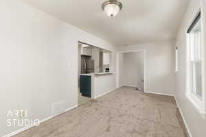 Unfurnished living room with light carpet, a sink, visible vents, and a wealth of natural light