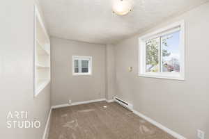 Carpeted spare room featuring a baseboard radiator, a textured ceiling, and baseboards