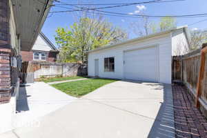 Detached garage featuring central AC, concrete driveway, and fence