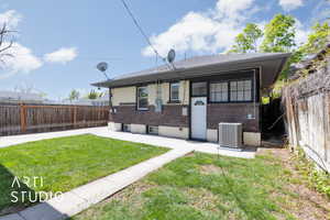 Back of property with central AC unit, a lawn, a fenced backyard, a patio, and brick siding