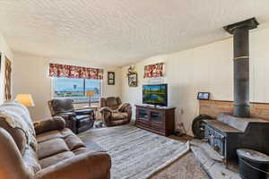 Carpeted living room with a wood stove and a textured ceiling