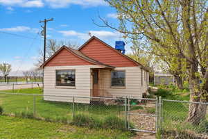 Bungalow-style house with a chimney, a front lawn, a gate, and a fenced front yard
