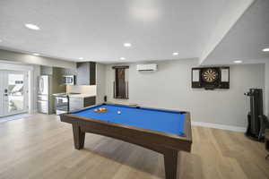 Game room with baseboards, recessed lighting, a textured ceiling, and a wall unit AC