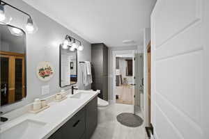 Full bath featuring marble finish floor, toilet, a sink, and double vanity