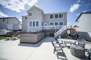 Back of property with fence, a hot tub, a patio, and stairs