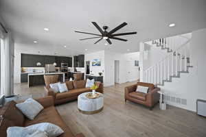 Living area featuring light wood-type flooring, visible vents, recessed lighting, a ceiling fan, and stairs