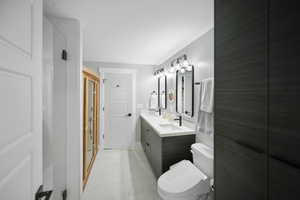 Bathroom with double vanity, marble finish floor, toilet, and a sink