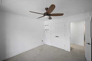 Unfurnished bedroom featuring carpet floors, a closet, baseboards, and ceiling fan