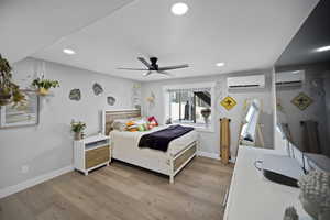 Bedroom featuring light wood finished floors, baseboards, a wall mounted AC, and recessed lighting