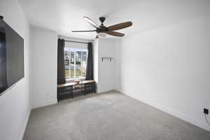 Carpeted empty room featuring a ceiling fan and baseboards