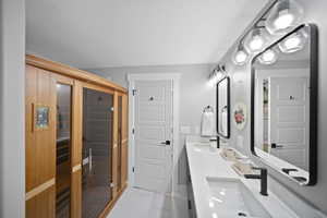 Bathroom with double vanity, marble finish floor, baseboards, and a sink