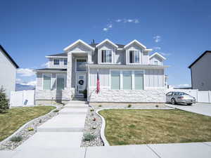 View of front of house with a front lawn, fence, stone siding, and board and batten siding
