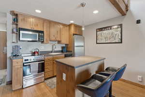 Kitchen featuring dark countertops, a sink, light wood-style floors, and appliances with stainless steel finishes